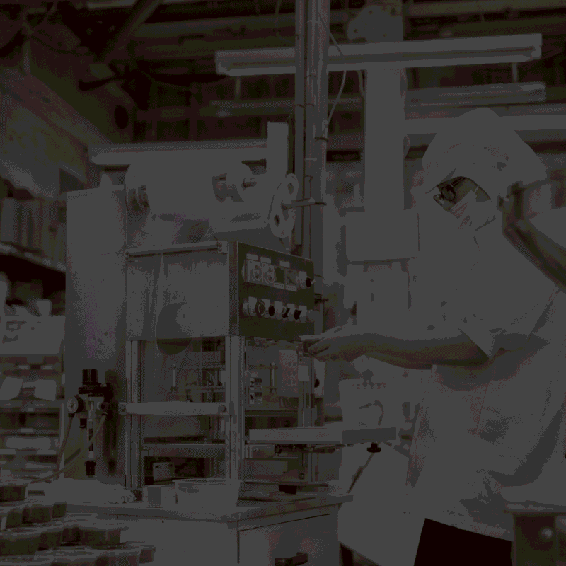 Food manufacturing worker operating packaging equipment in a production facility, highlighting the importance of reliable manufacturing partnerships in food and beverage licensing.