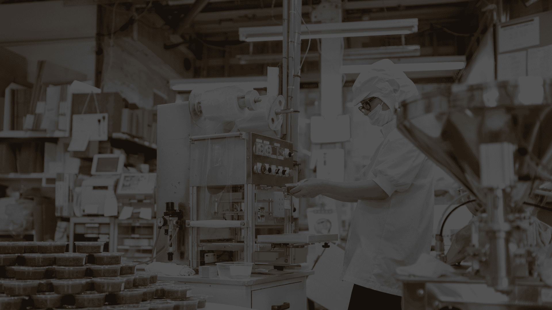 Food manufacturing worker operating packaging equipment in a production facility, highlighting the importance of reliable manufacturing partnerships in food and beverage licensing.